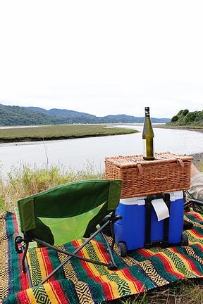 picnic set up on a colorful blanket in front of a lake.