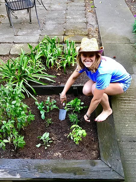woman with a hat on gardening and smiling