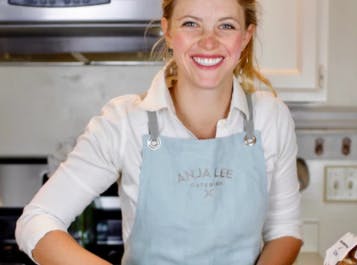 Woman cooking in a blue apron smiling at the camera