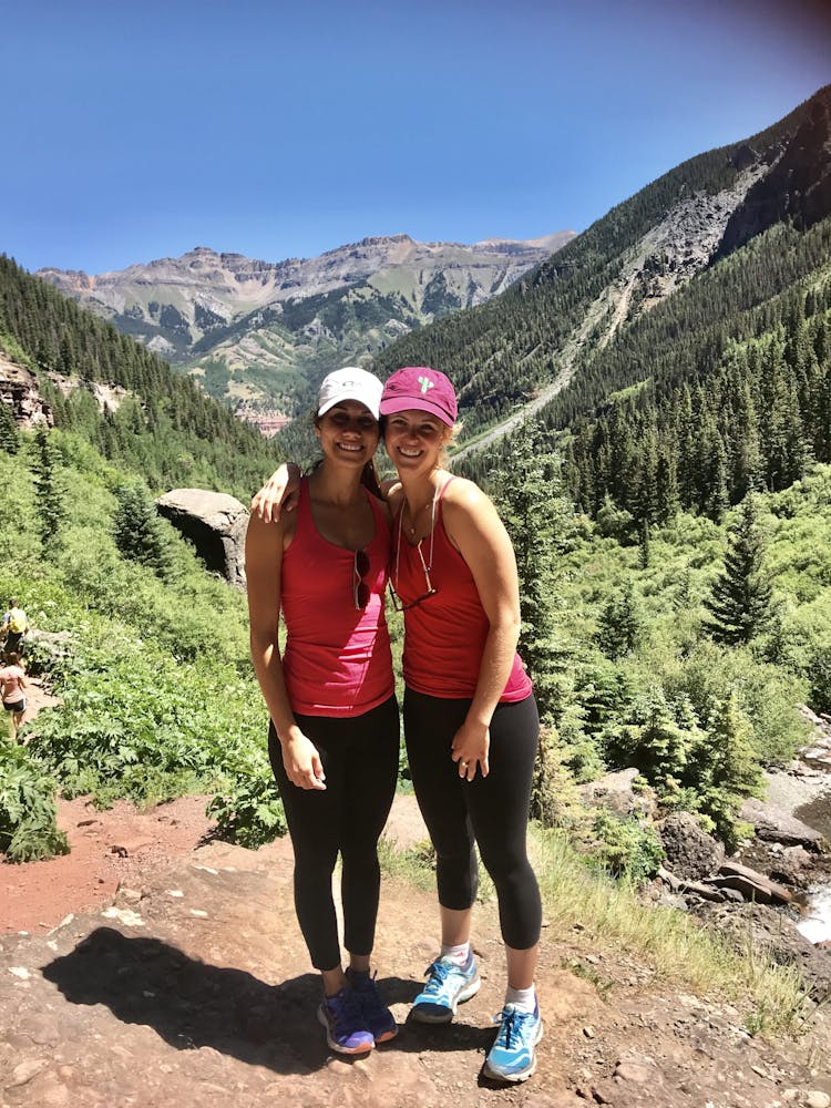 two women smiling with trees and mountains behind them