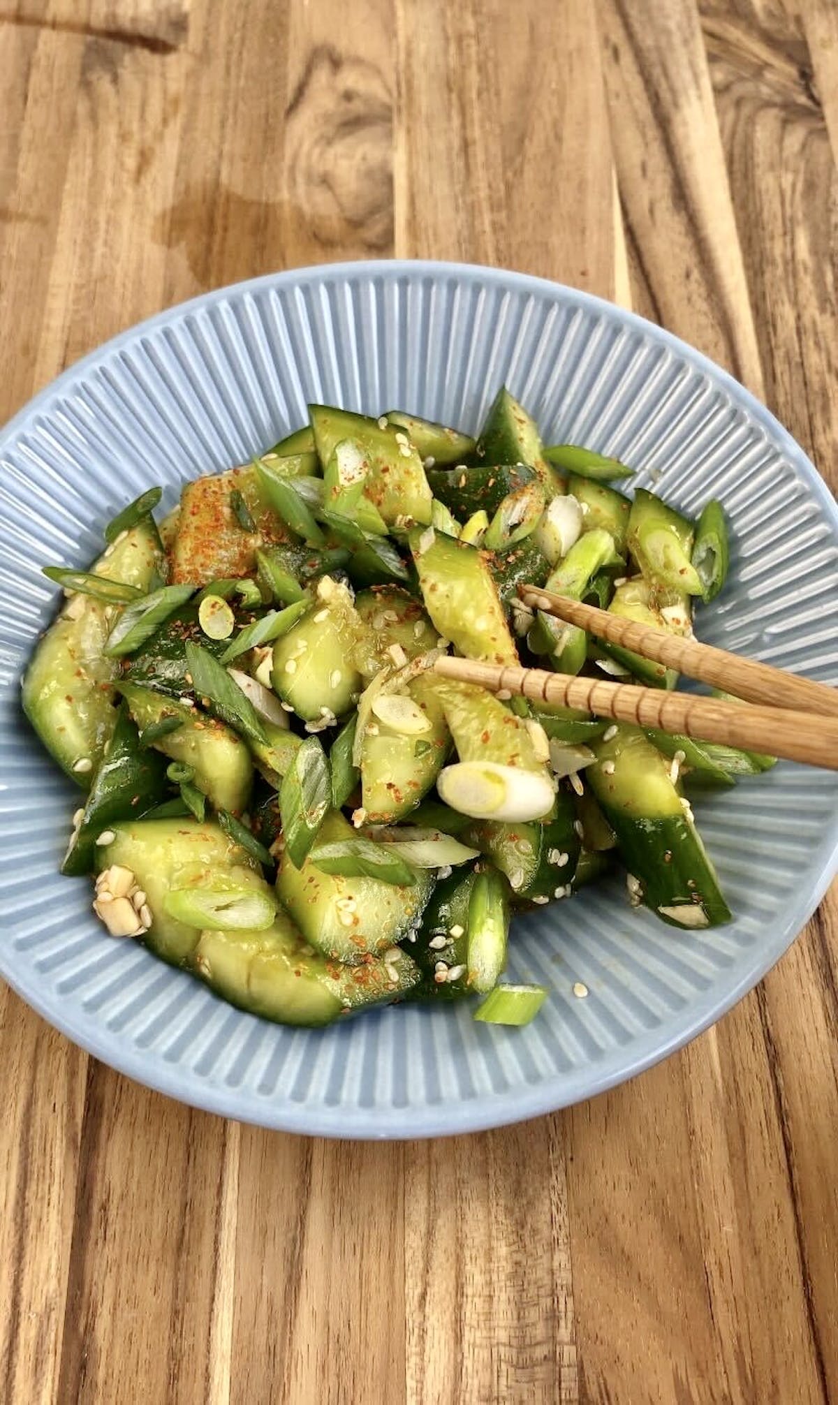 smashed cucumber salad in a blue bowl with chopsticks