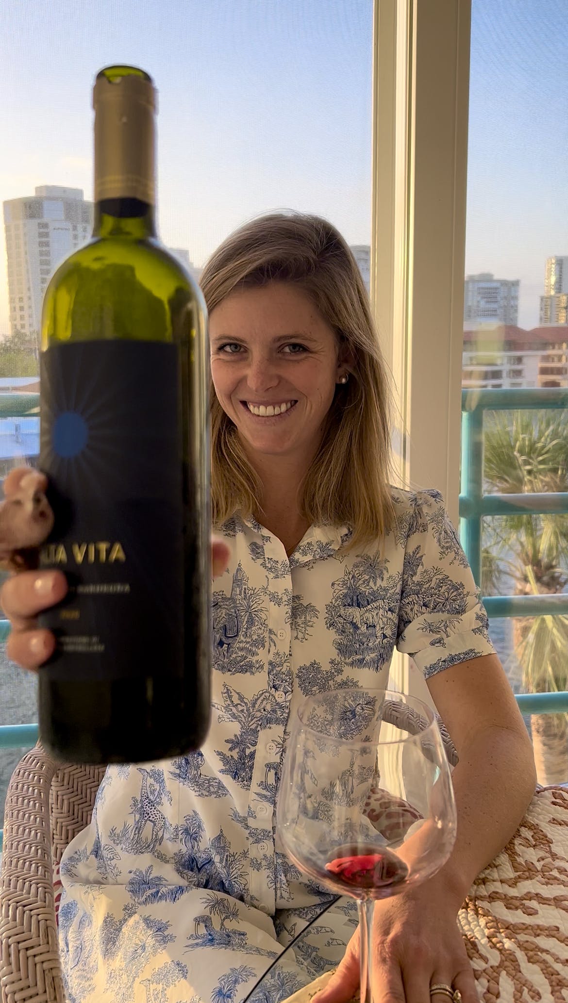 Chef Anja smiling holding up a bottle of red wine