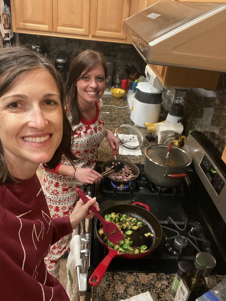 two women smiling with cooking over the stovetop